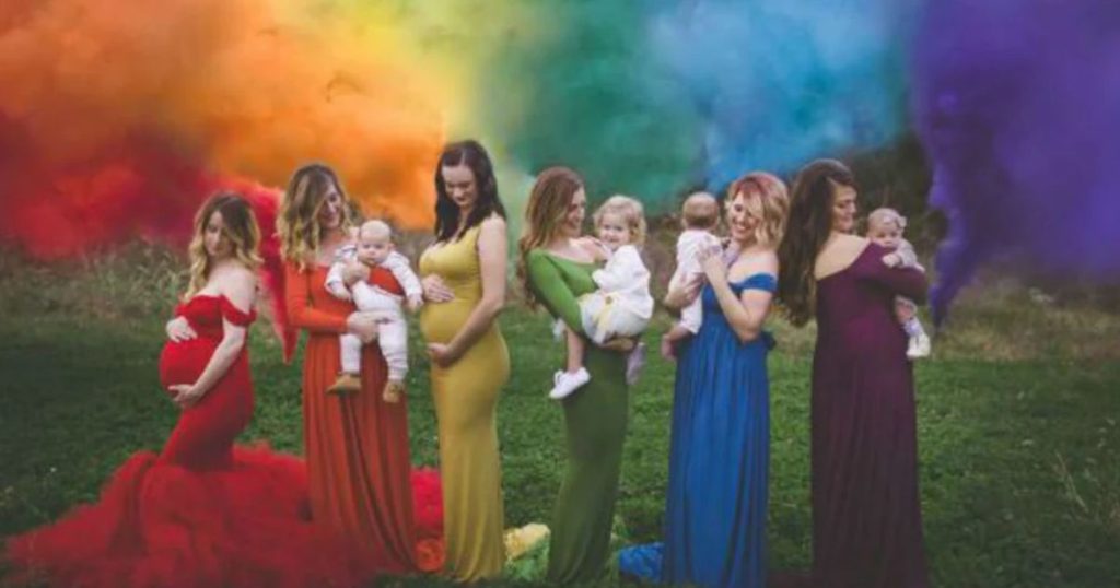 A group of pregnant women and mothers standing together at the National Rainbow Baby Day event. They are smiling and holding hands, radiating joy and hope. The event is a celebration of the babies born after a previous loss or miscarriage, symbolized by the rainbow.