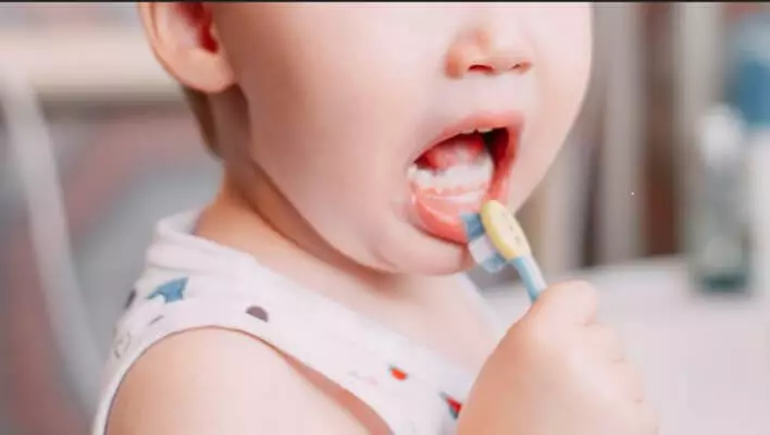 A parent using natural remedies, such as applying herbal or homeopathic remedies with tooth brush, to treat cavities in their baby's teeth.